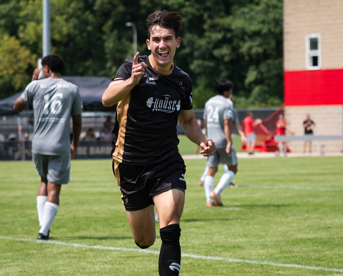 A happy soccer player running on the field towards the camera