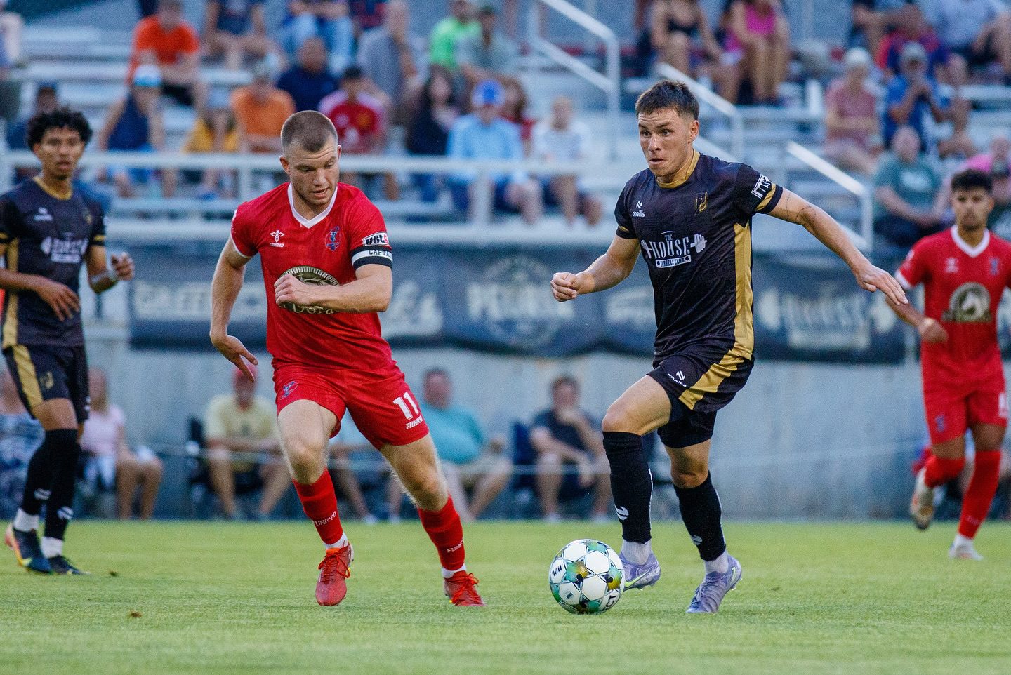 Two opposing soccer players on the field rushing towards the goal