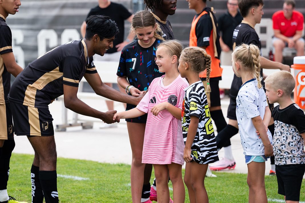 A Peoria City Soccer player saying hello to children fans